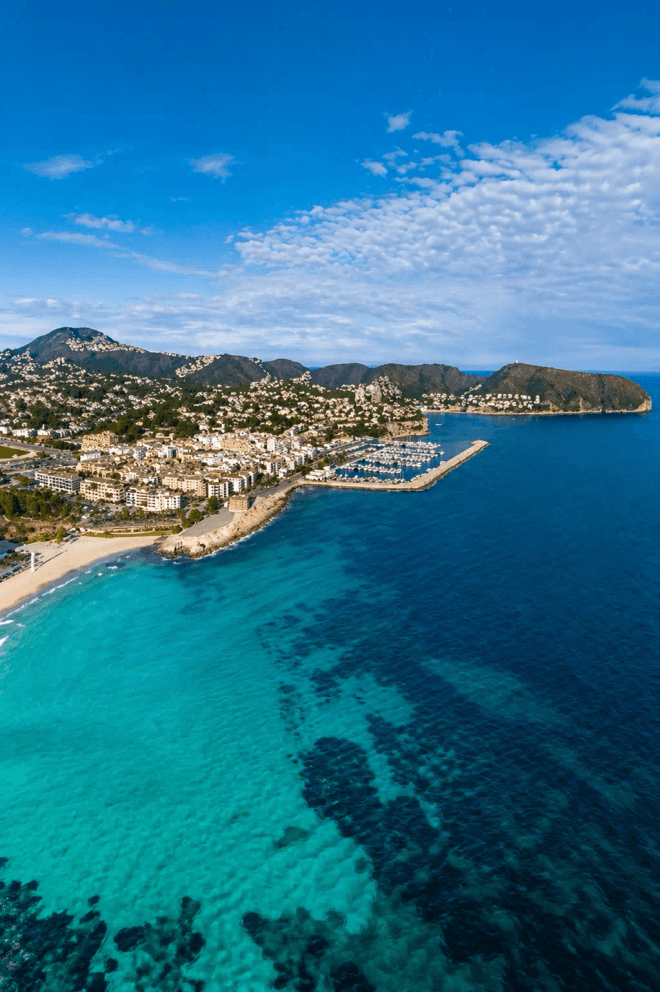 Aerial view of Moraira port, village and coastline with clear turquoise sea on the Costa Blanca